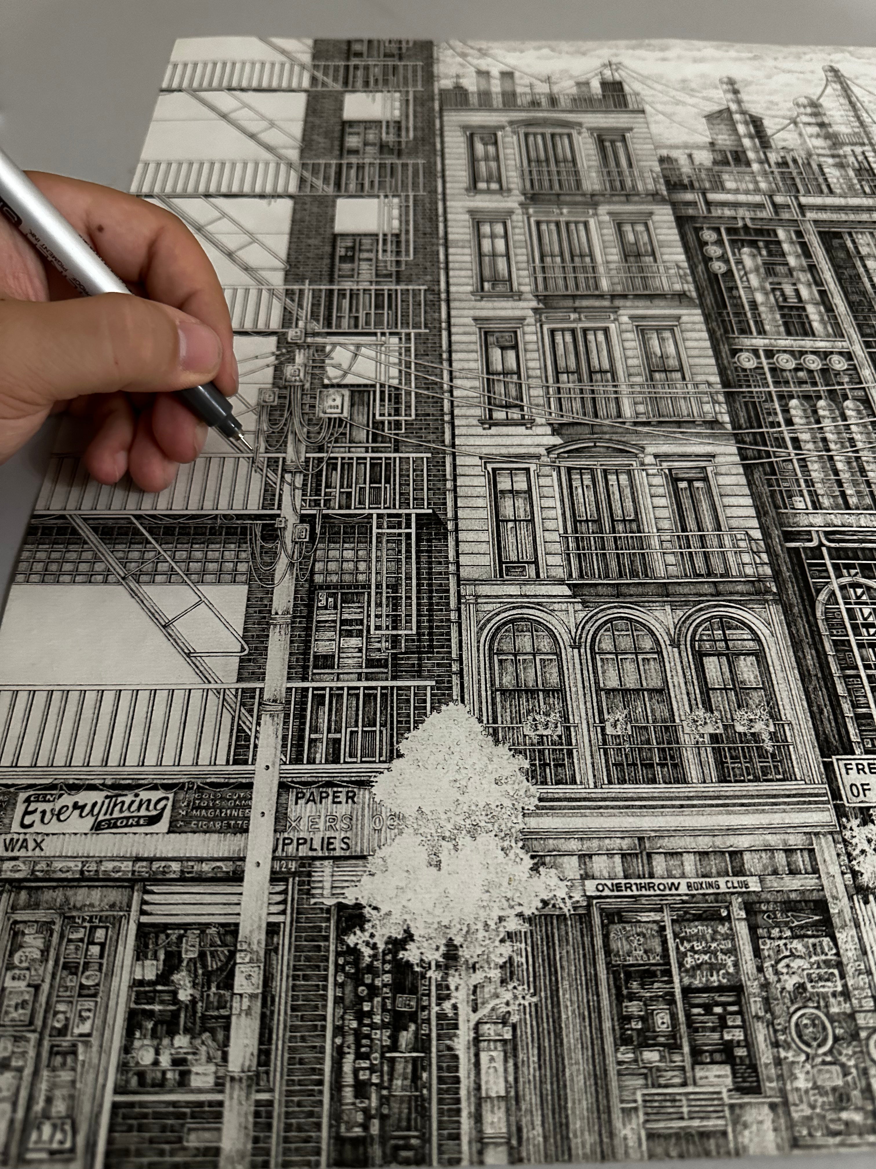Hand-drawn cityscape with detailed buildings and a ladder, using newspaper as a drawing medium.